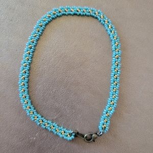 14k gold plated beads hand stitched surrounded by teal beads.